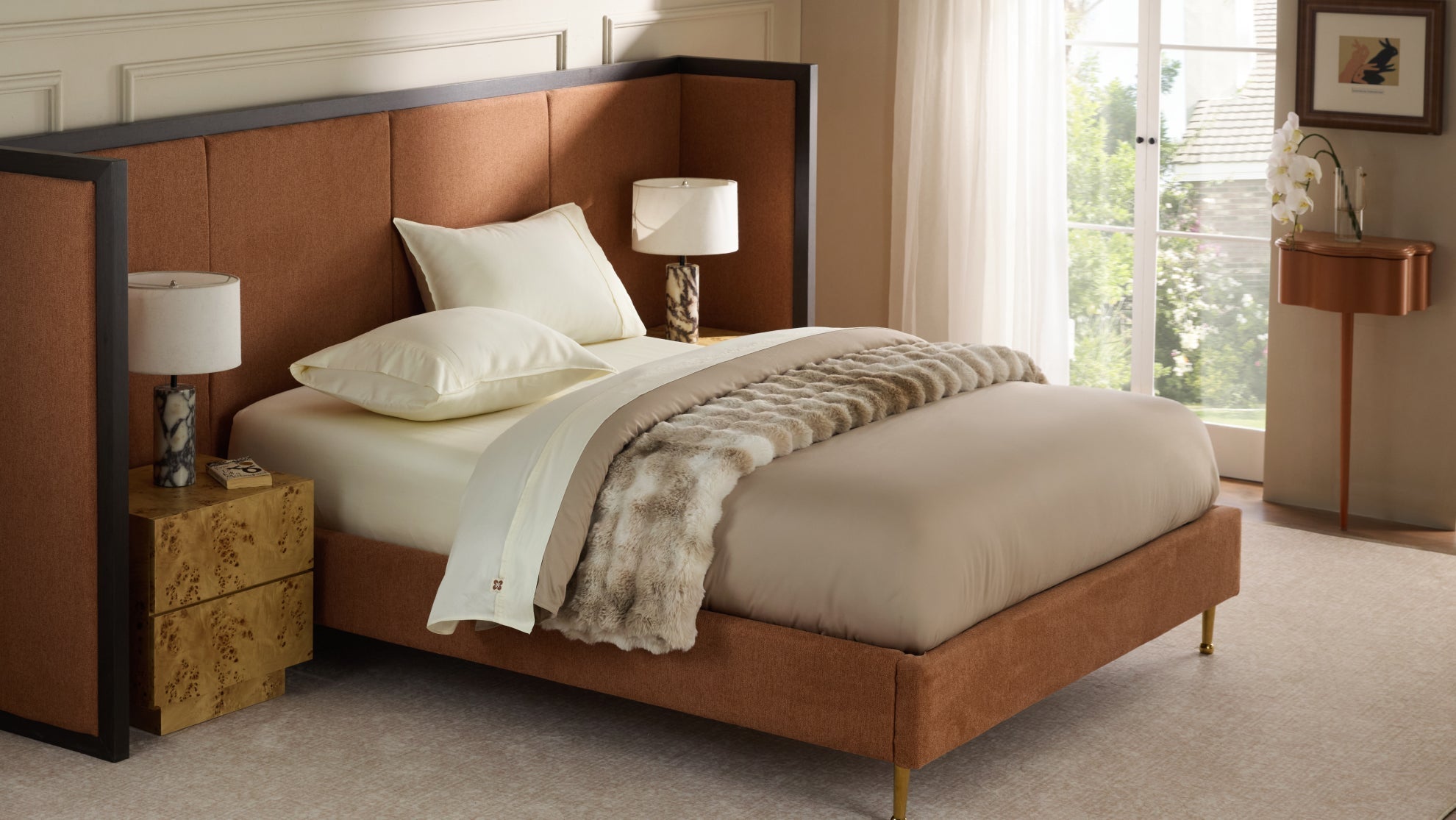 Luxury bedroom featuring cream Egyptian cotton sheets, a plush faux fur blanket, and a stylish burnt orange upholstered headboard.