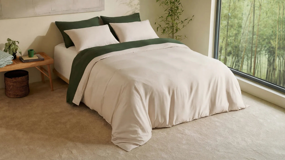 Cream bed set with dark green pillowcases and duvet accents in a bedroom
