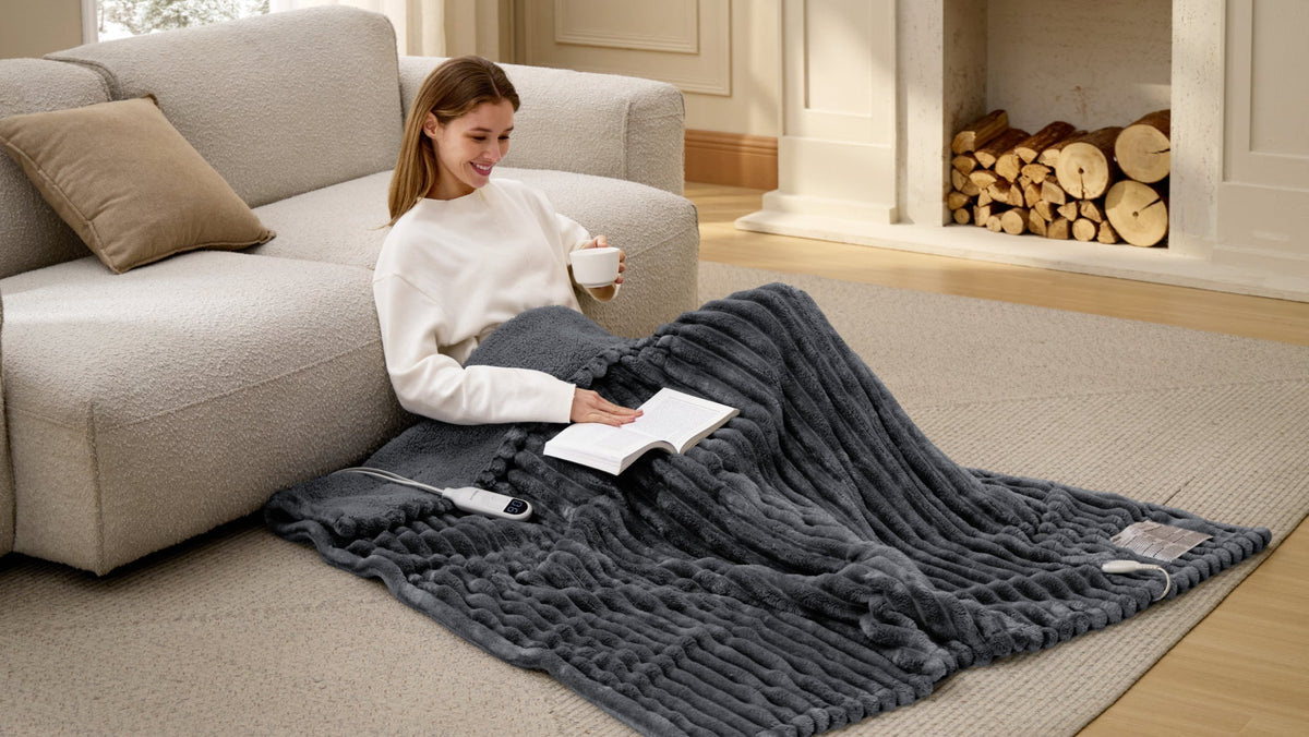 Smiling woman with a mug sitting on a gray blanket by a sofa