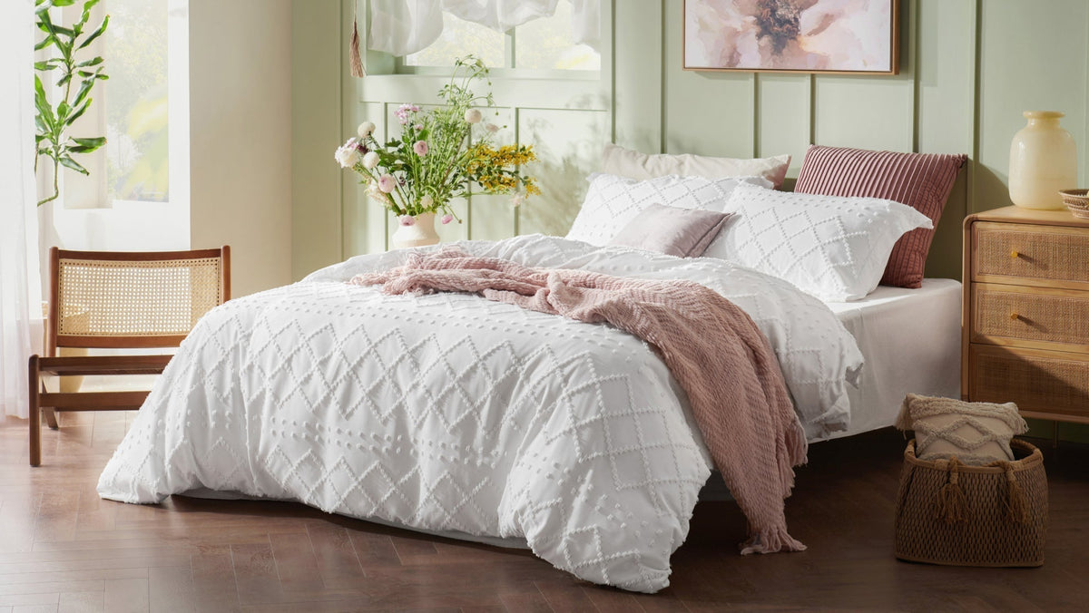 A perfectly made bed with a white textured duvet cover, showing the neat result of following this guide.