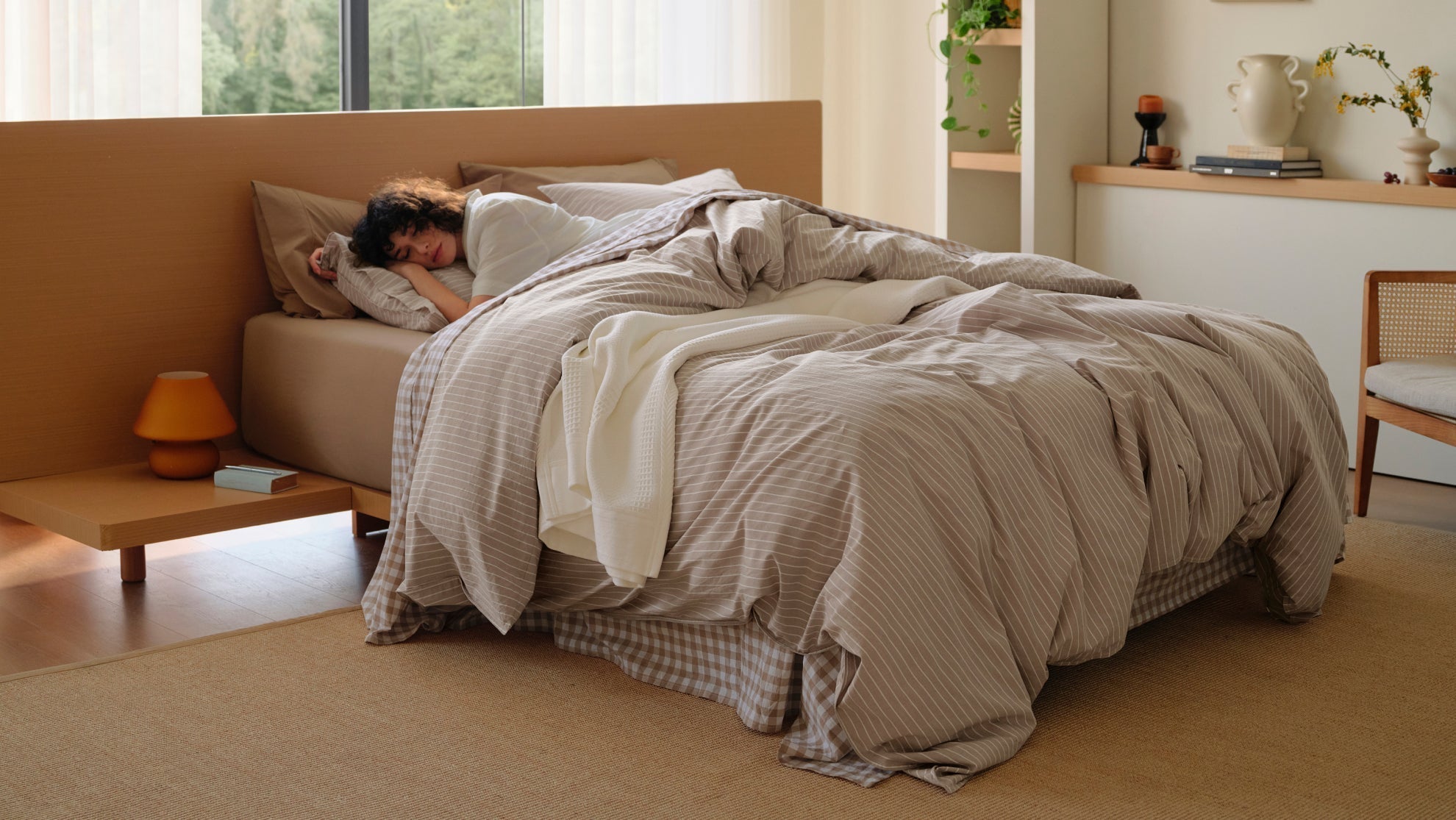 A woman sleeps peacefully under a perfectly sized striped duvet cover. Choosing the correct bedding size ensures maximum comfort and a beautiful, cozy drape for your bedroom setup.