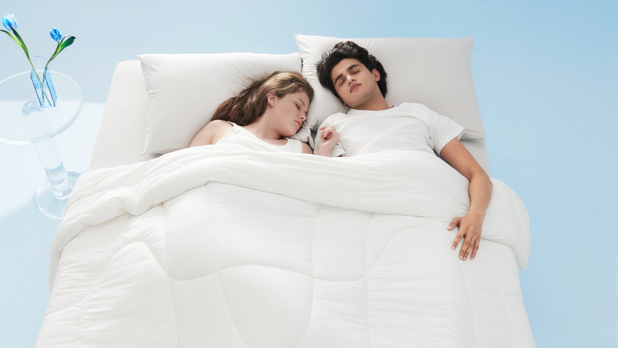 Couple sleeping under white bedding in a cool bedroom