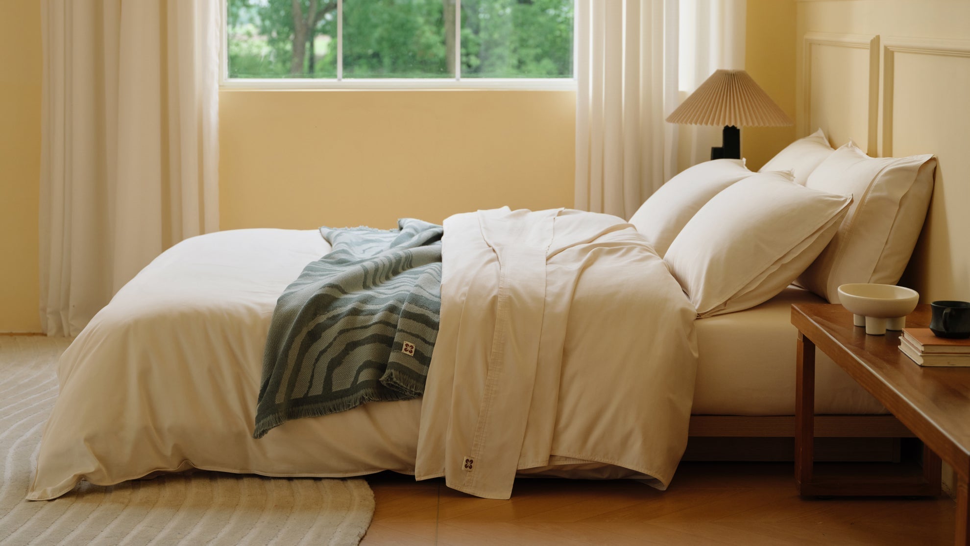 Stylish layered bed with white duvet and green throw blanket showcasing fall bedroom decor