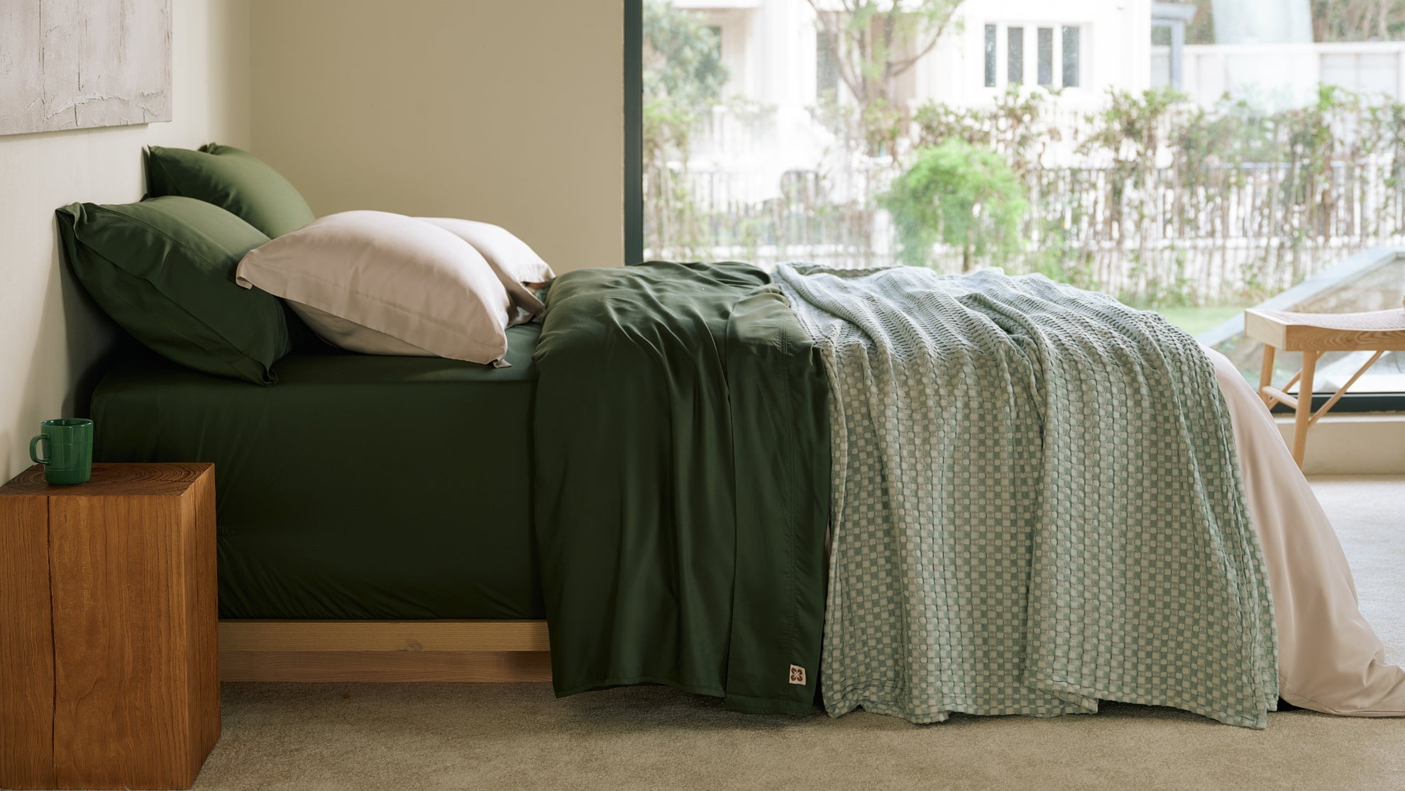 Cozy fall bedroom showcasing deep earthy green bedding with neutral accent pillows and textured throw blanket