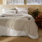 PureWoven Serene Blend Smart Warmth Bundle with striped blanket & controllers on bed.