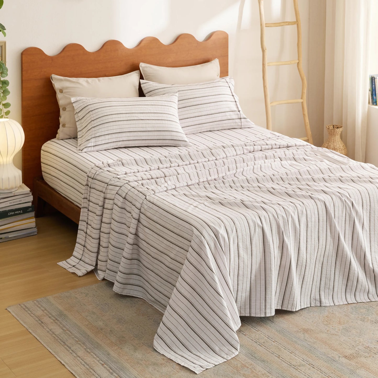 Cotton-Like striped sheet set with pillowcases on a bed with scalloped wooden headboard.