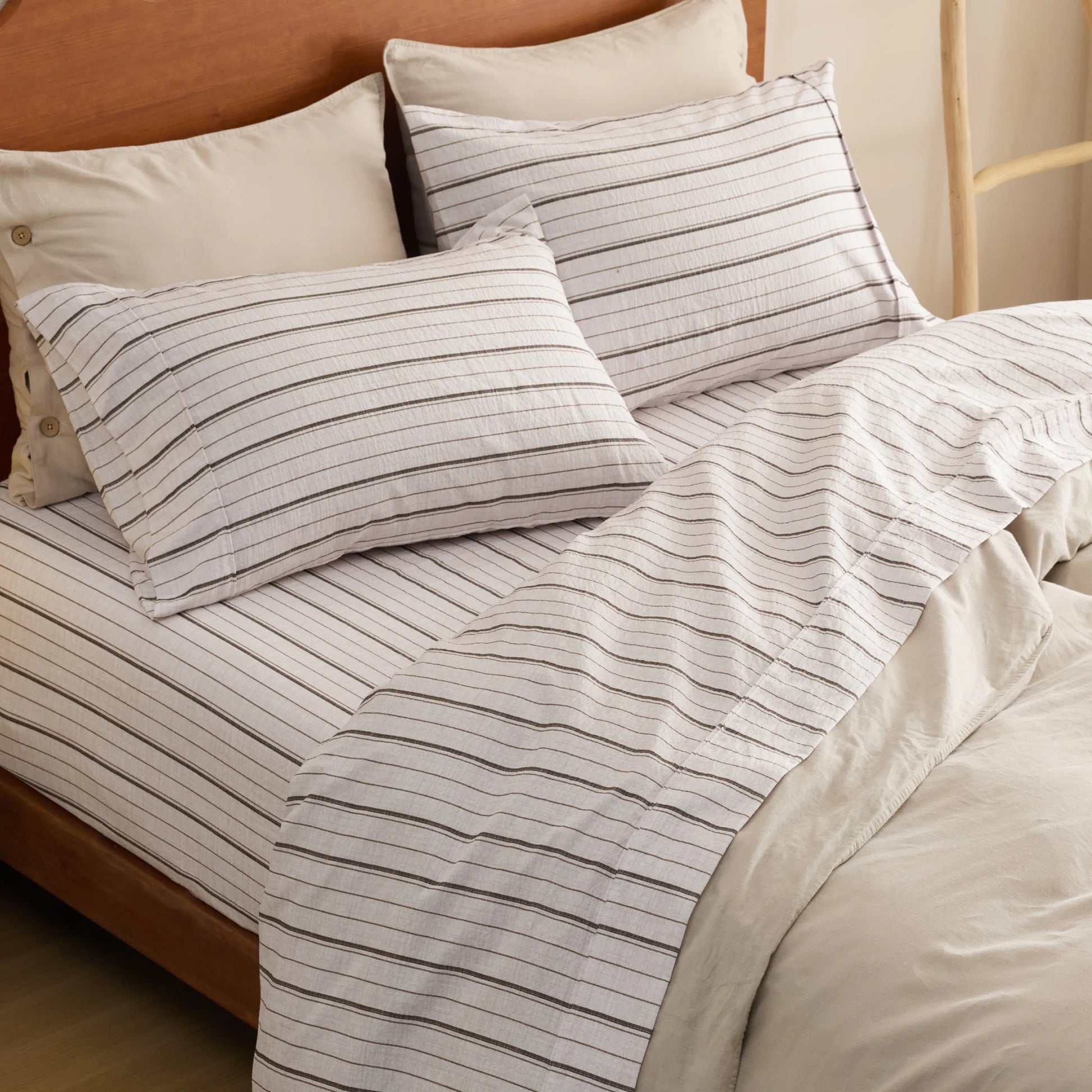 Cotton-Like white and dark striped sheet set with neutral pillowcases.