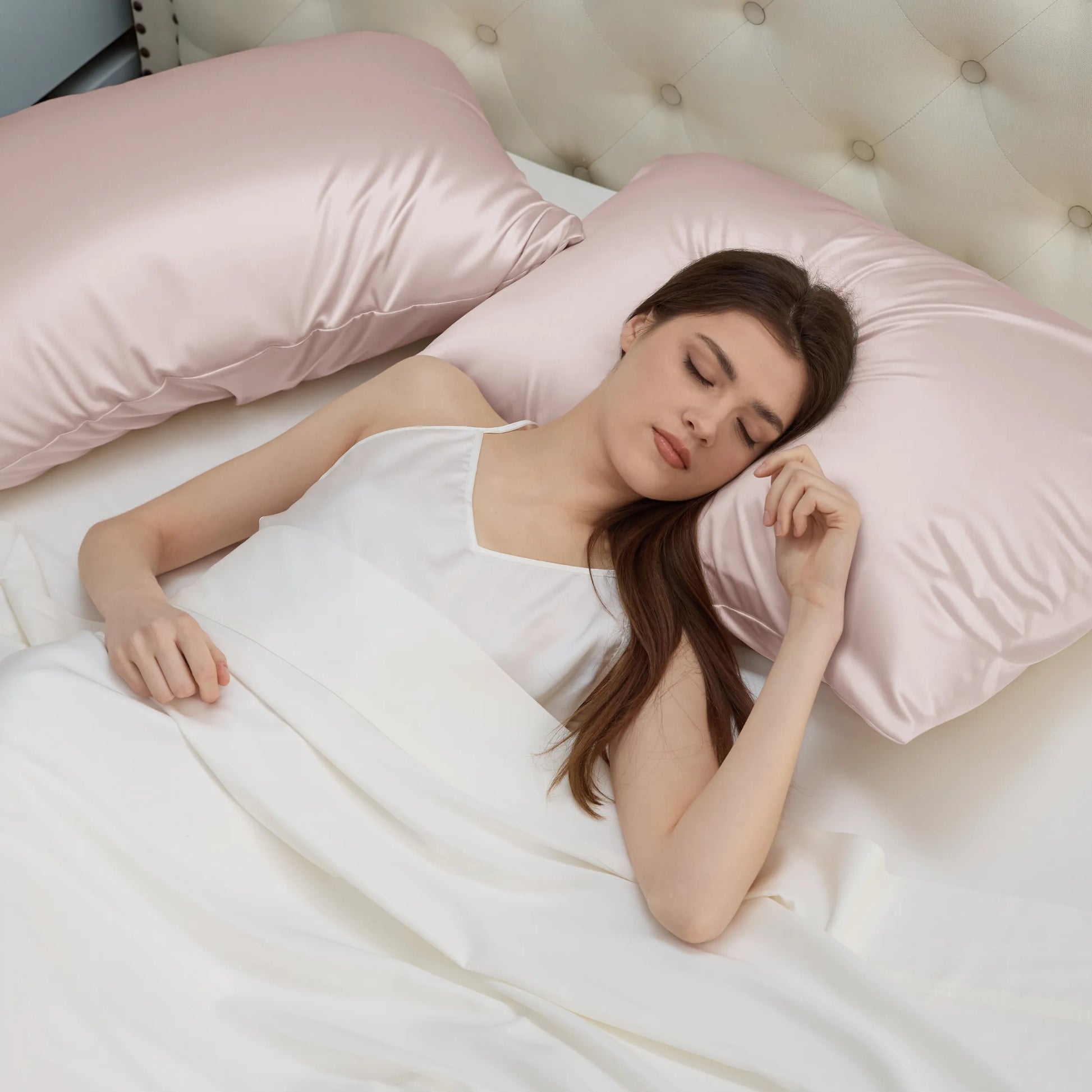 Woman sleeps on pink nylon-spandex Beauty Sleep Pillowcases for cool comfort.