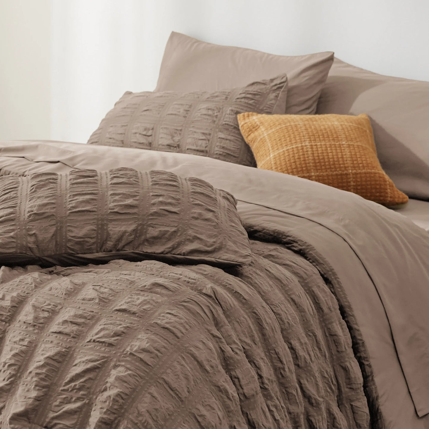 Seersucker Bed-in-a-Bag set in taupe, featuring textured comforter and decorative plaid pillow.