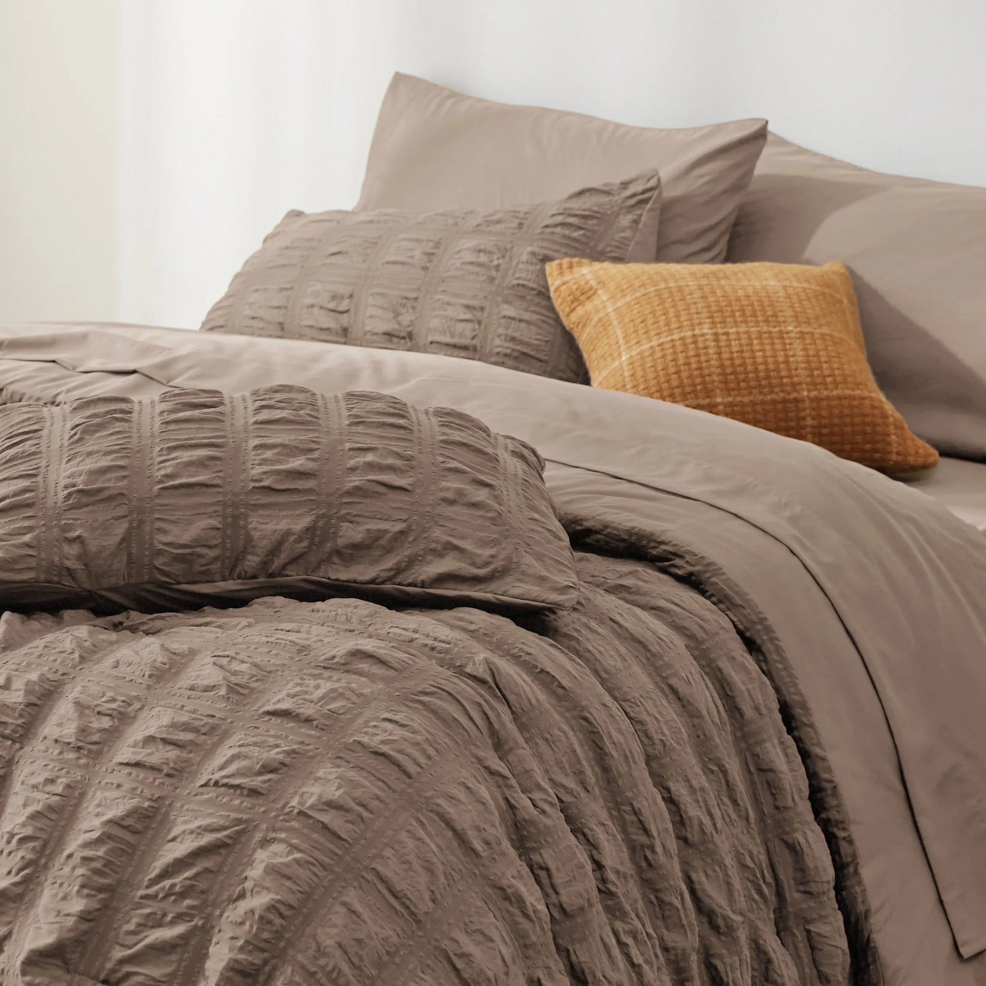 Seersucker Bed-in-a-Bag set in taupe, featuring textured comforter and decorative plaid pillow.