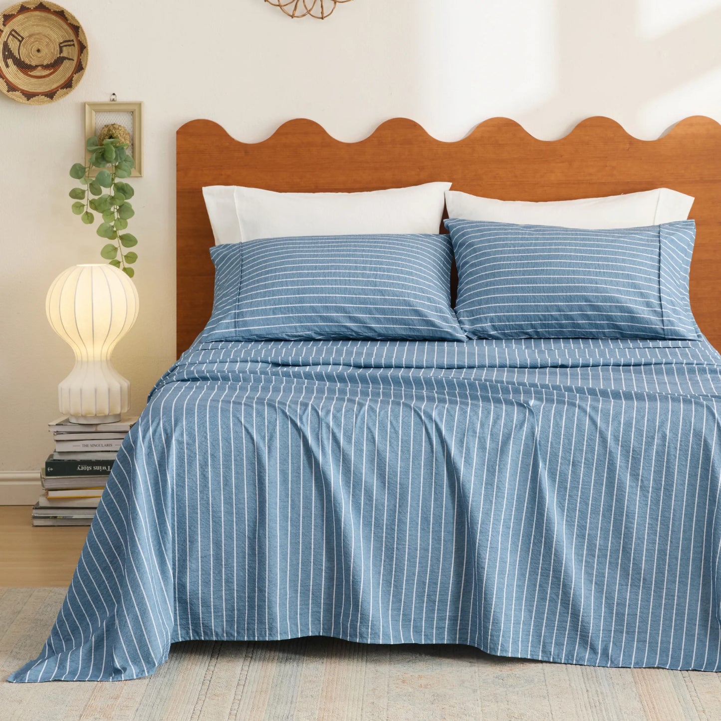 Cotton-like blue and white thin striped sheet set with pillowcases on a bed.