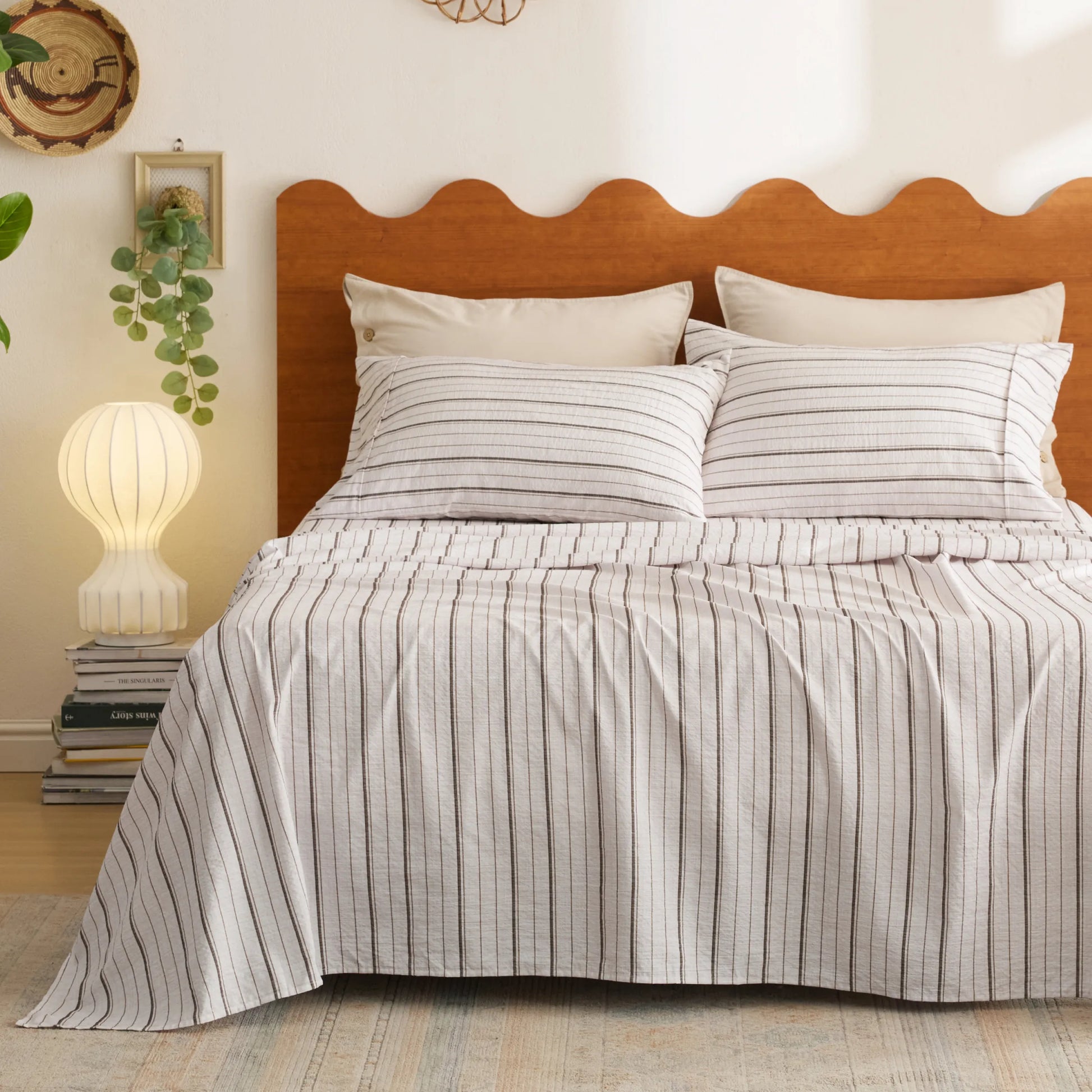 Soft cotton-like striped sheet set with thin charcoal vertical stripes on a bed.