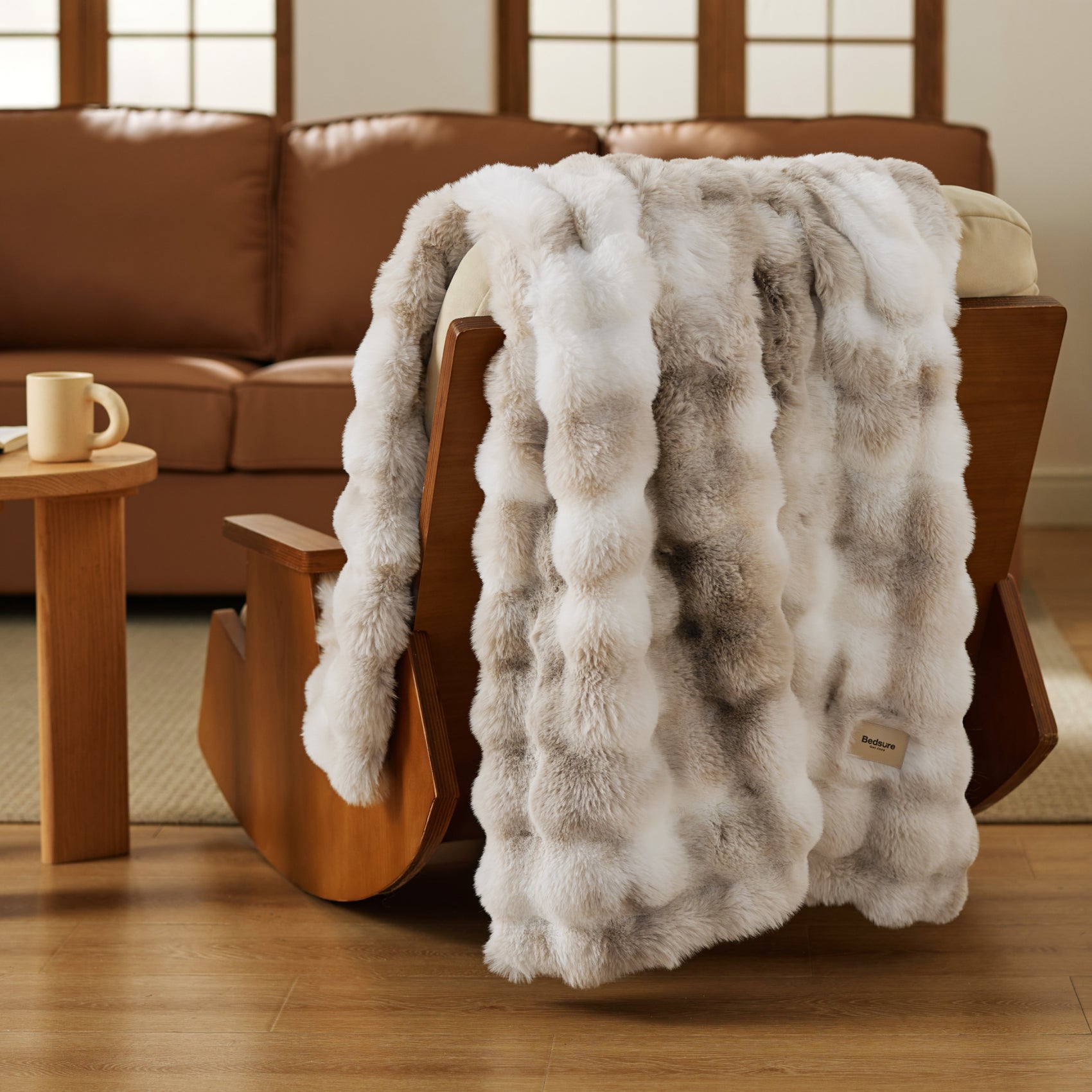 Plush luxe bubble faux fur blanket with cream and grey stripes, draped on rocking chair.
