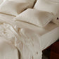 Creamy white organic cotton waffle weave bedding bundle with soft sheets, pillows, and draped blanket.