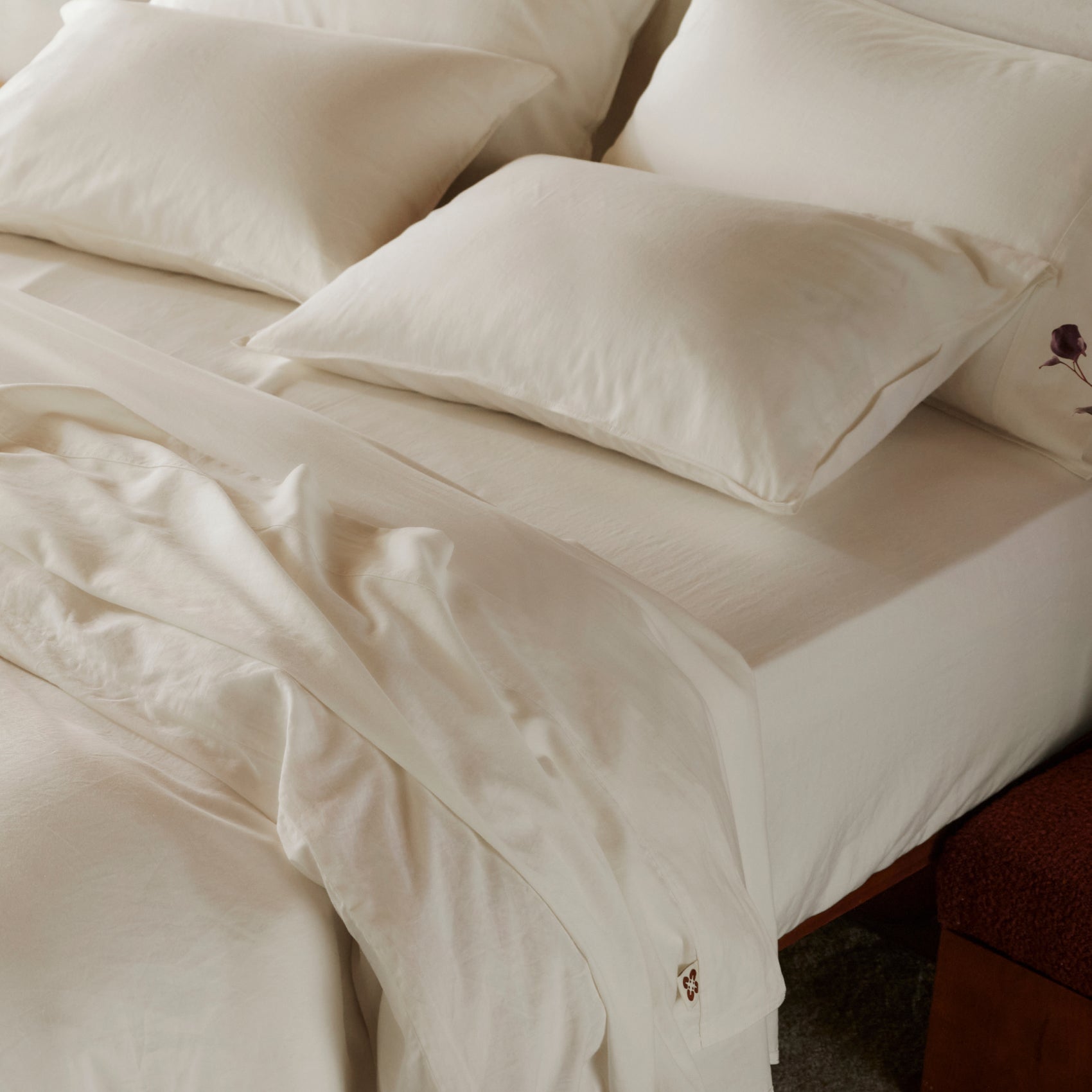 Creamy white organic cotton waffle weave bedding bundle with soft sheets, pillows, and draped blanket.
