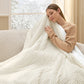 Woman enjoying warmth under a cozy, ribbed coconut white heated blanket.