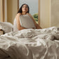 Woman relaxing in bed with slub cotton bedding from the cozy bundle.