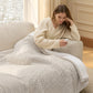 Woman relaxing under a cozy, ribbed Smart Warmth blanket while holding controller.