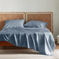 Silky soft blue rayon derived from bamboo sheet set on bed with rattan headboard.