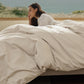 Woman relaxing on a bed with luxurious beige slub cotton plush bedding.