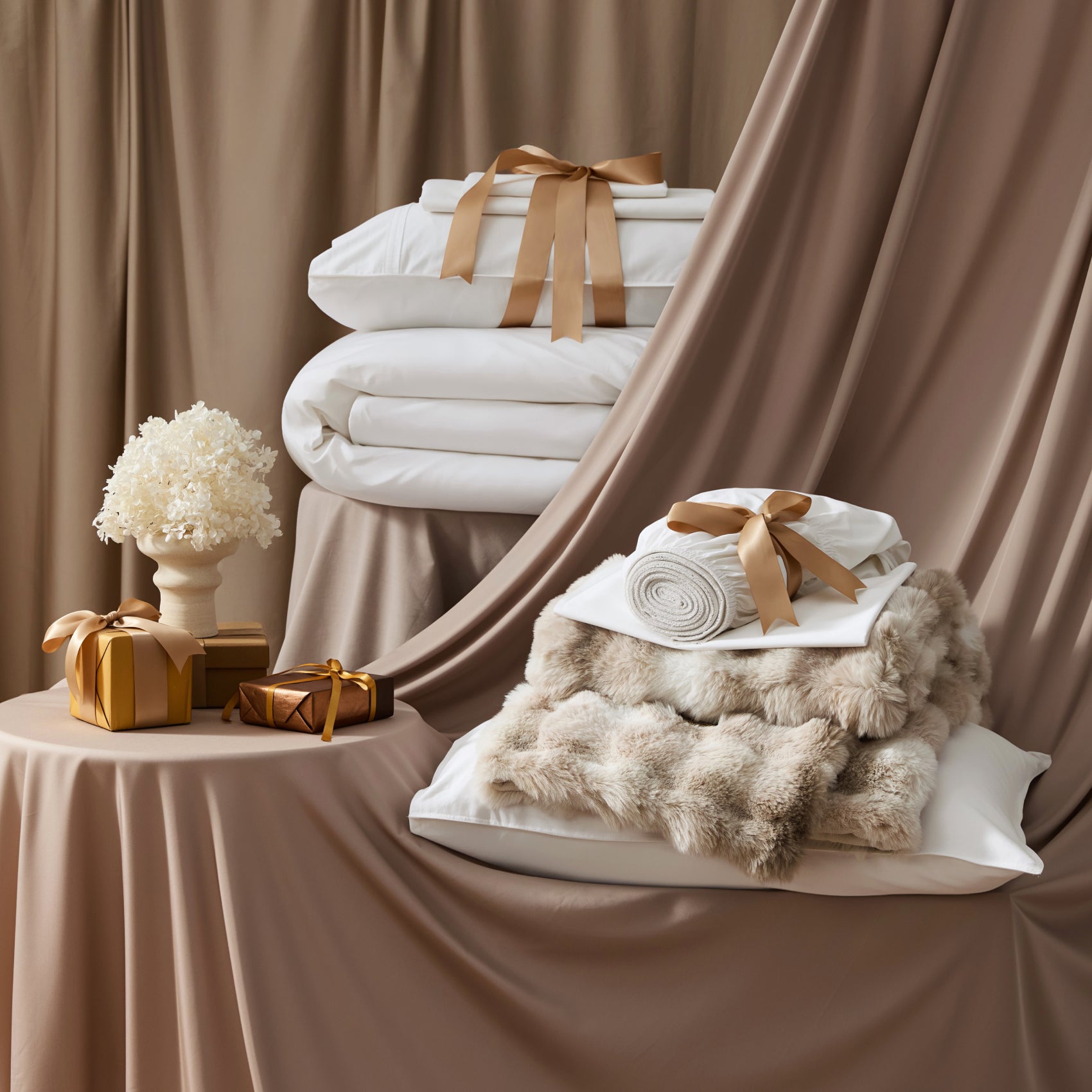PureWoven™ Organic Cotton Plush Luxe Bundle with white bedding, faux fur blanket, and gifts.