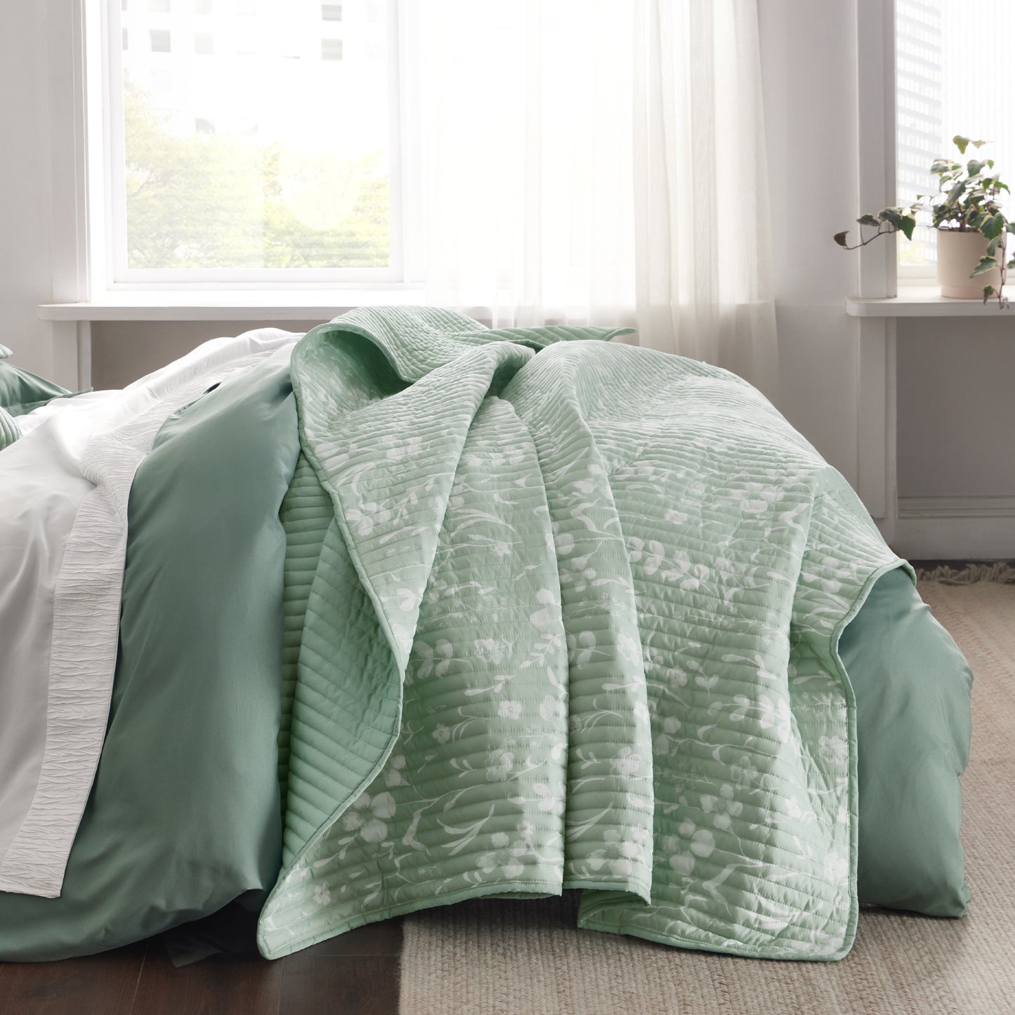 Botanical Quilt Set: Light green quilt with white floral pattern on bed.