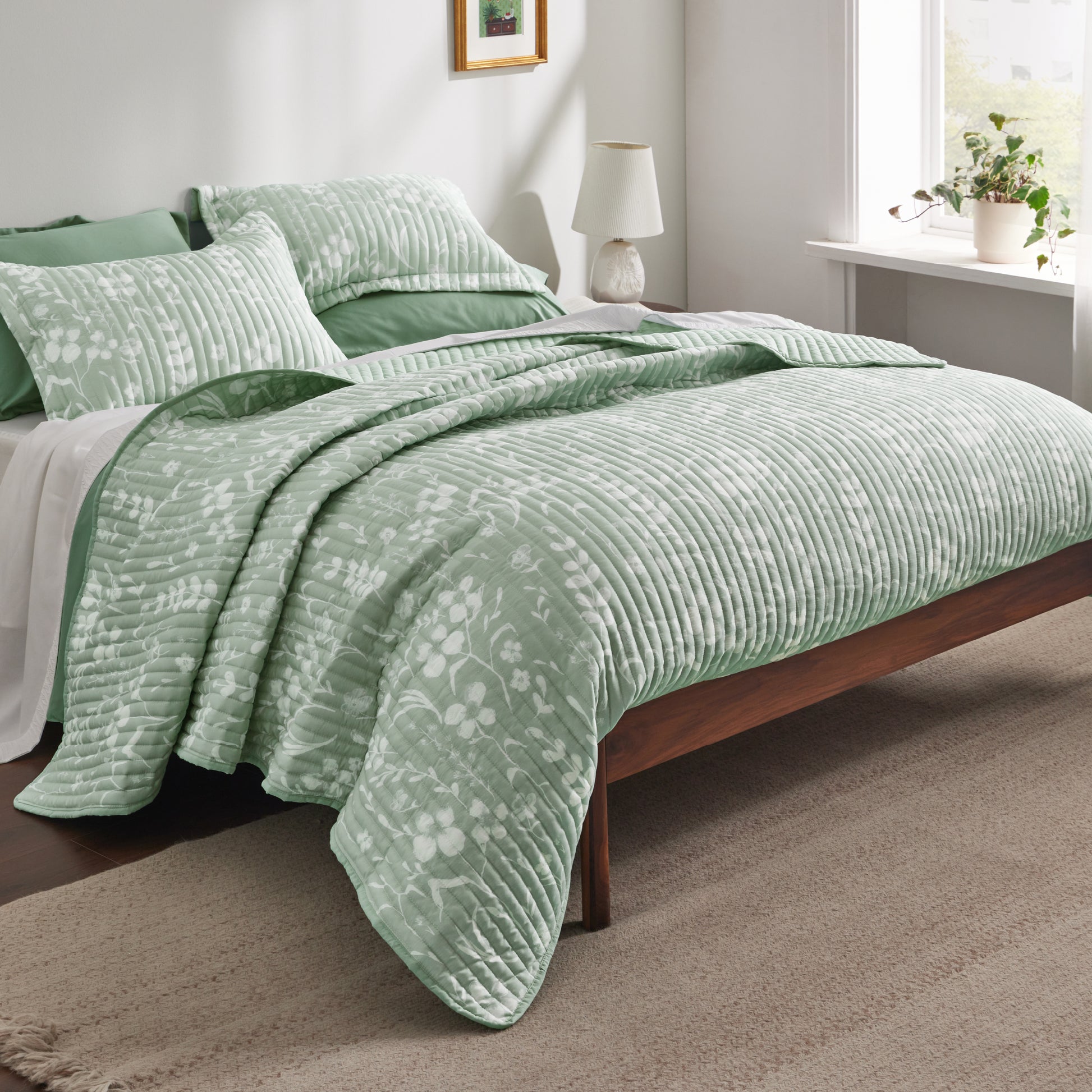 Green botanical quilt set with white floral pattern and diagonal quilting.
