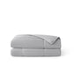 Soft grey nylon cooling comforter, folded, with white piping and breathable texture.