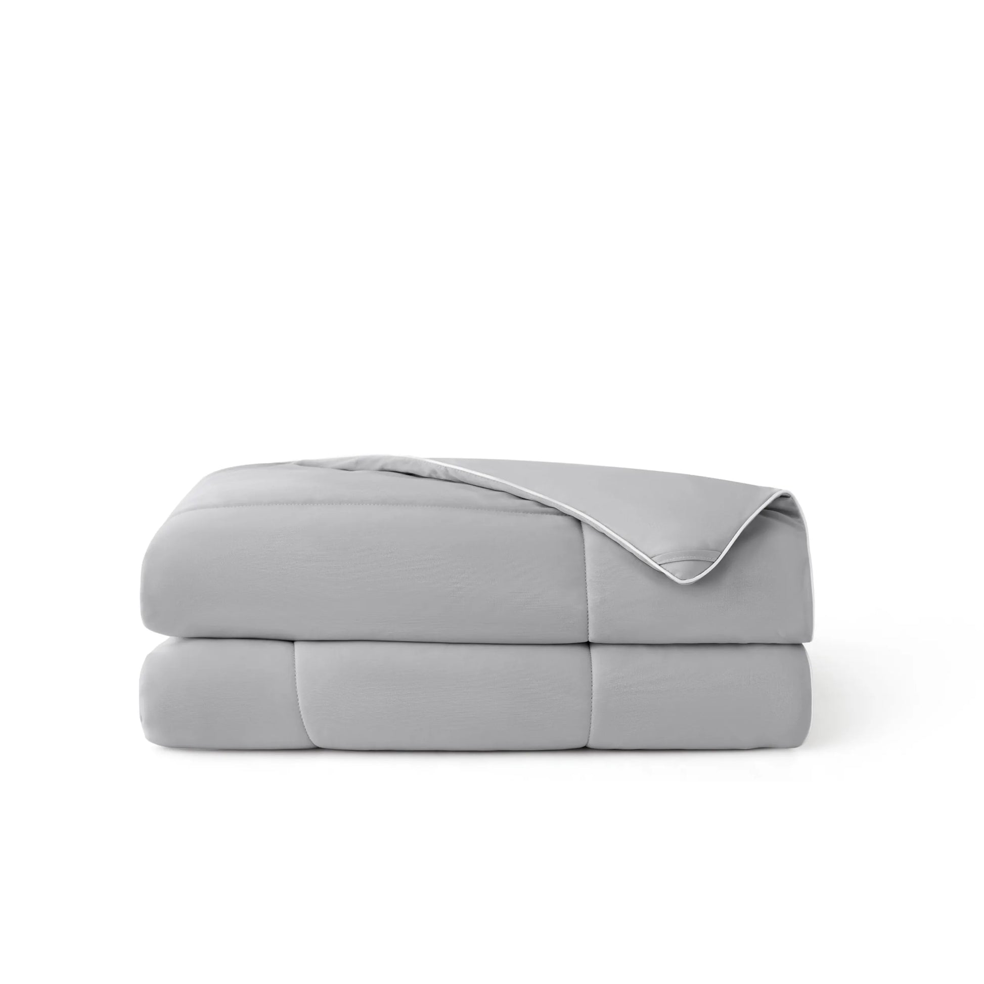 Soft grey nylon cooling comforter, folded, with white piping and breathable texture.