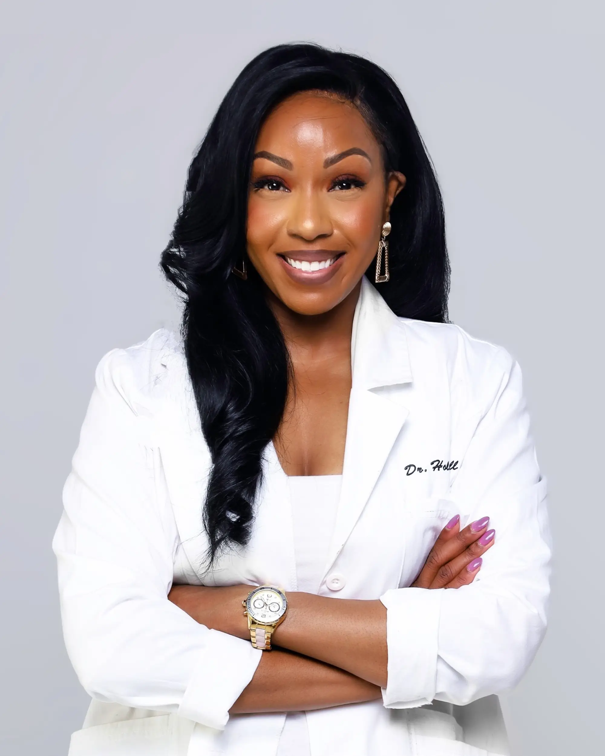 Dr. Angela wearing a white lab coat against a gray background 