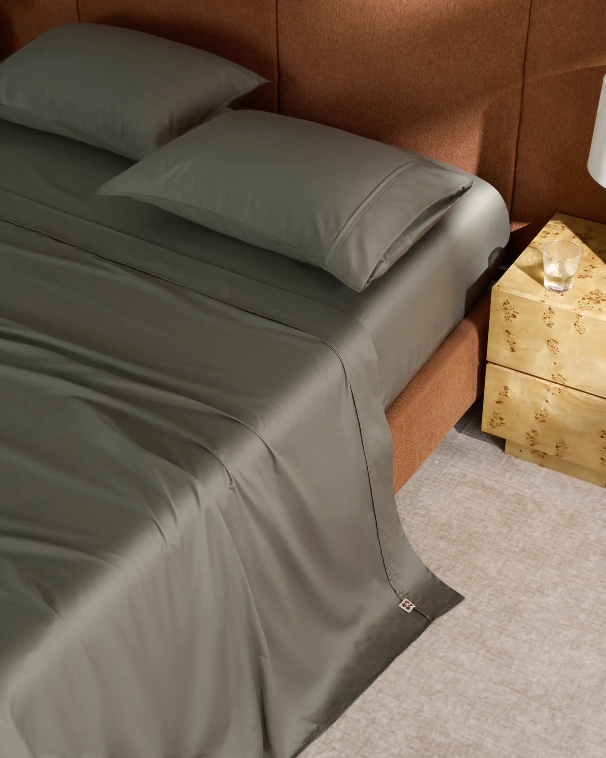 Bed with green bedding and a wooden nightstand in a bedroom setting 