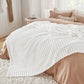 GentleSoft white polyester blanket with plush wavy ribbed texture draped on a bed with taupe bedding.
