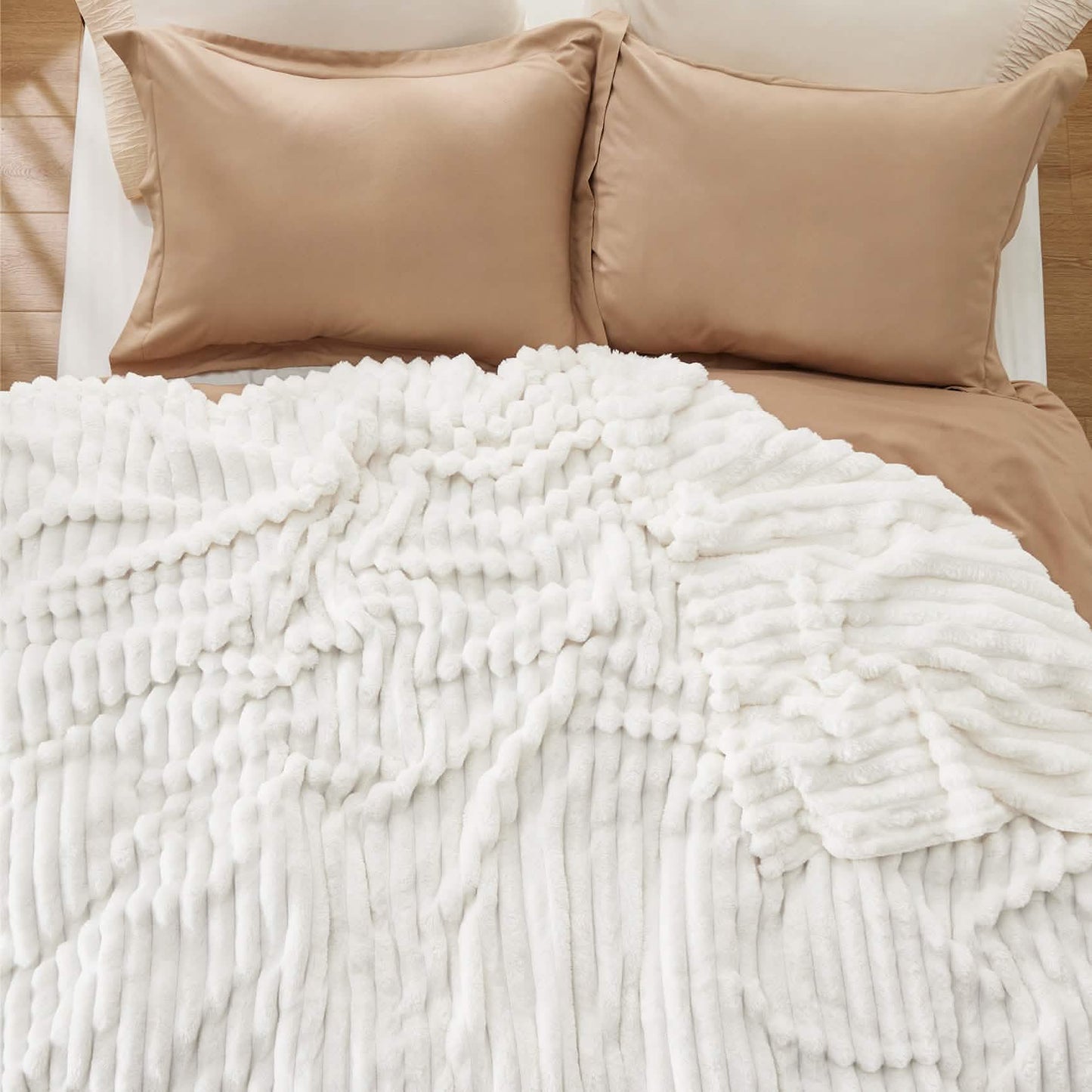 GentleSoft white polyester blanket with prominent wavy texture draped on a bed with taupe bedding, showcasing plush softness.