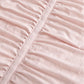 Pink polyester comforter close-up showing ruched fabric texture and decorative seam.
