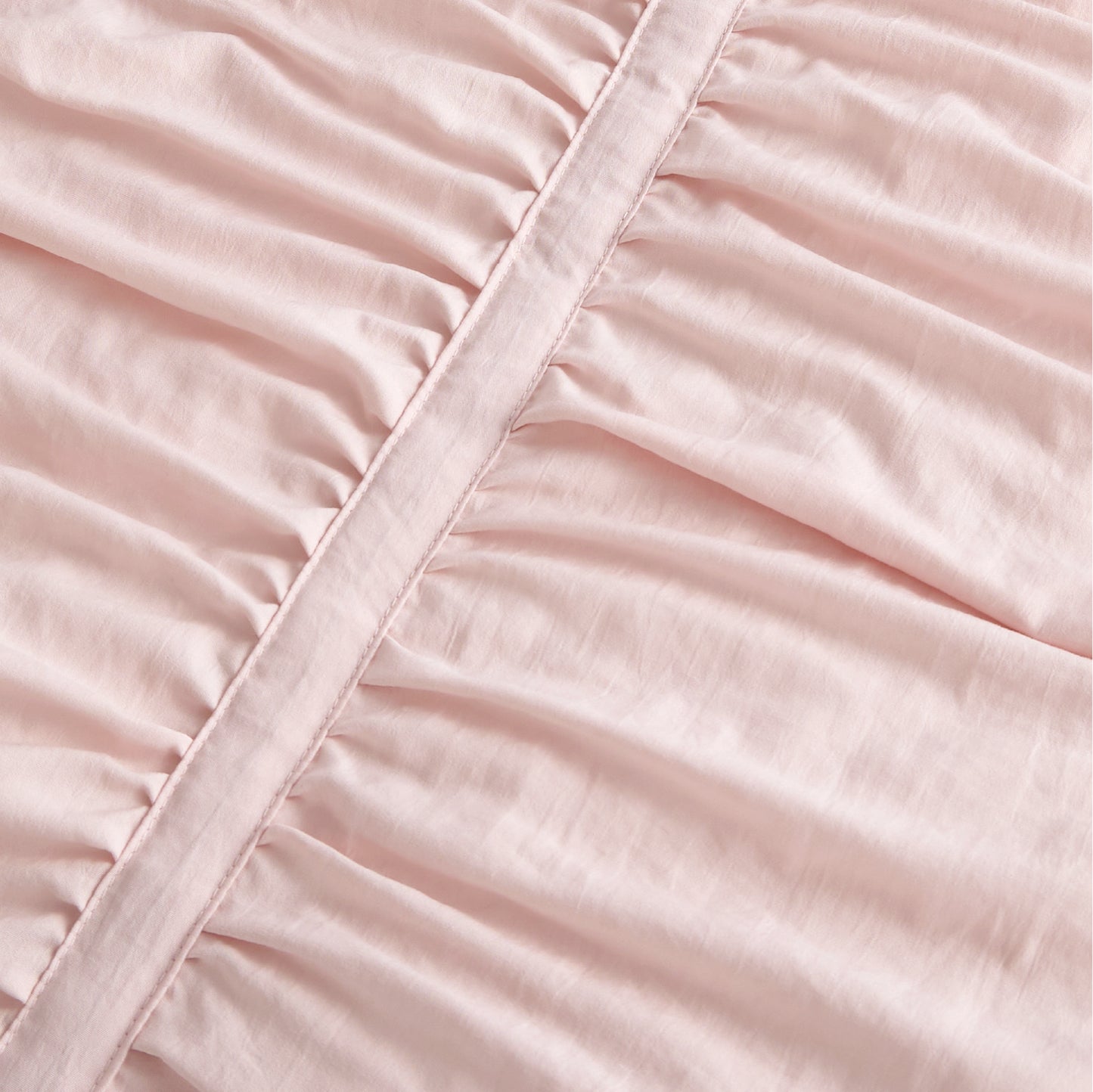 Pink polyester comforter close-up showing ruched fabric texture and decorative seam.